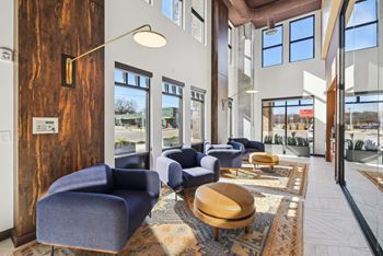a lobby with blue chairs and tables and windows at Link Apartments® Broad Ave, Memphis, TN